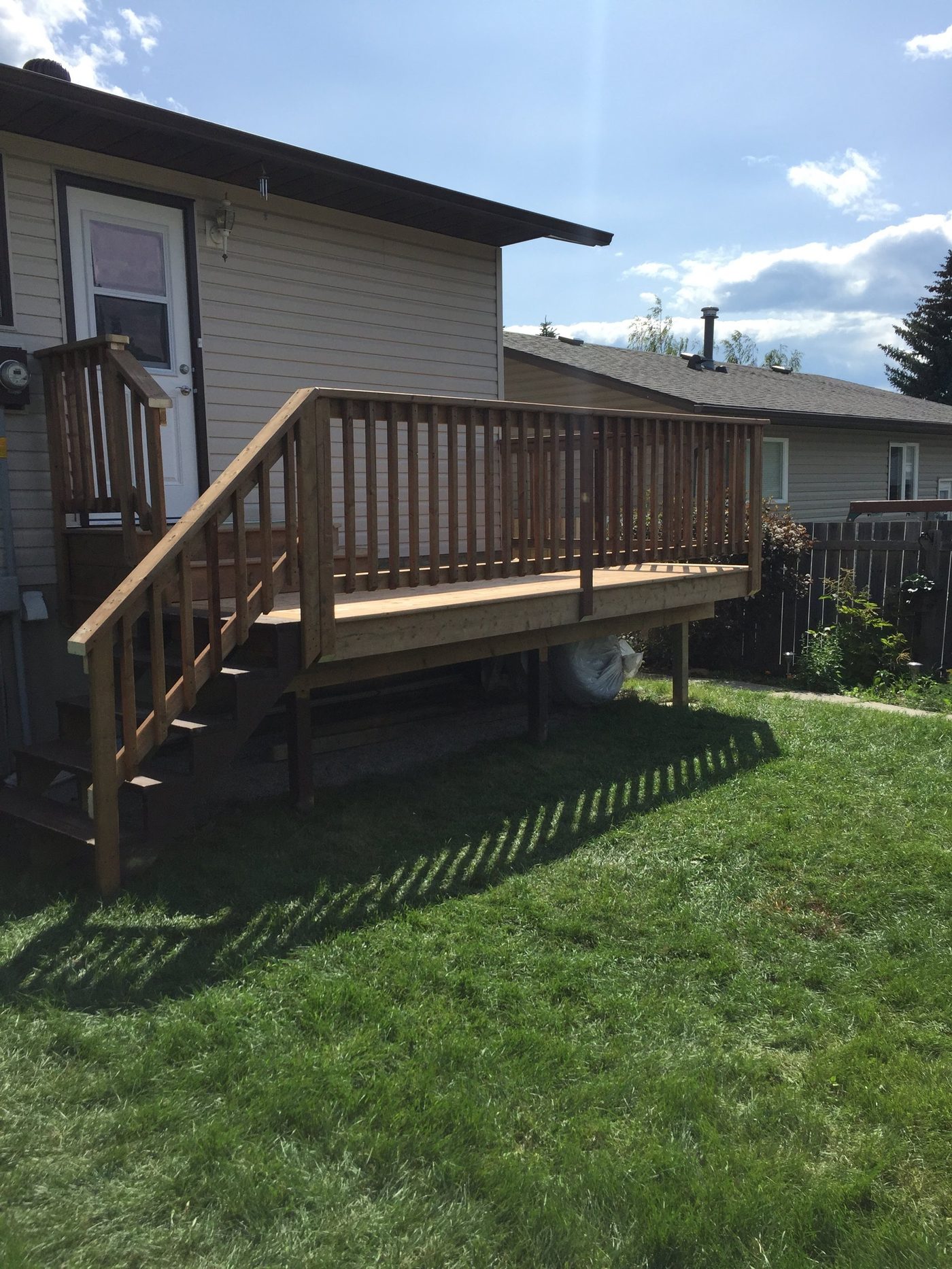 Stained wood deck with railings and stairs onto a green lawn